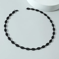 Détail d'une chaîne à maillons noirs brillants avec fermoir mousqueton sur fond gris - Collier / Noir