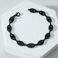 Dettaglio di un bracciale a chicco di caffè nero lucido su un piedistallo di pietra bianca - Bracciale / Nero