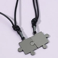 Close-up of interlocking puzzle pendants in black stainless steel on woven cords - Black