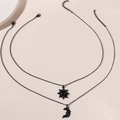 Detailed view of black layered necklaces with sun and moon pendants on beige background - Black Set