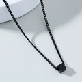 Close-up of black cube pendant on steel chain necklace with minimalist industrial design - Black Cube