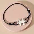 Dettaglio del bracciale a corda nera regolabile con ciondolo a forma di puzzle lucido - Cordino Nero