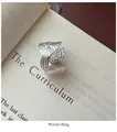 Detailaufnahme eines S925 Sterling Silber Webrings im Vintage-Stil auf Buchseiten - Einstellbar Offen / Gewebter Minimalistischer Stil (JZA100)