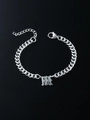 Silver Cuban chain bracelet with Gothic initial pendant on reflective black surface - Letter M