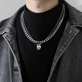 Vue macro d'un collier double chaîne cubaine avec pendentif lettre S gothique homme - S