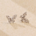 Boucles d'oreilles papillon en argent avec zircons sur une surface en pierre beige - Argent 925 / Or Blanc