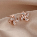 Orecchini a mulino a vento in oro rosa con zirconi lucidi su sfondo di seta - Oro rosa