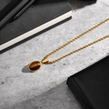 Macro-opname van gouden roestvrijstalen ketting met ovale tijgeroog steen hanger - Tijgeroog Hanger + Touwketting (PN-2199)