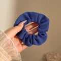Donkerblauwe geribbelde gebreide scrunchie in de hand tegen een beige achtergrond - #9 Donkerblauw Circa 9 Cm