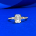 Emerald cut solitaire ring with gold pave band on a textured blue background - US 5 / Gold