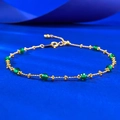 Macro shot of gold bracelet featuring green emerald-cut beads and flower accents - Adjustable Pull-out / Spinel Green