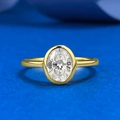 Eleganter goldener Ring mit ovalem Diamanten und Zargenfassung auf blauem Seidenhintergrund - US 5 / Gold