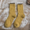 Senfgelbe Wollsocken mit dunkelbraunem Rippbündchen auf winterlichem Holzhintergrund - Einheitsgröße / Ingwergelb