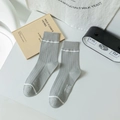 Graue Herrensocken mit Rippenstruktur und weißen Streifen in gemütlicher Szenerie - Einheitsgröße / Hellgrau