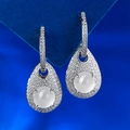 Macro shot of silver teardrop earrings with white stone and pavé setting on blue background - White Silica Jade Rhinestone Style (E513) / 925 Silver