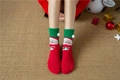 Detail of red and green coral fleece socks featuring Santa Claus patterns and fuzzy pom-poms - Red Green Santa Claus (No. 4)