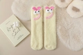 Detail von gelben Korallenfleece-Socken mit 3D-Augen und herzförmigen Applikationen - Hellgelber Herzstil / Weiß