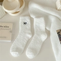 Dettaglio di calze bianche in pile corallo con ricamo a forma di occhi di cartone animato - Taglia unica / Bianco