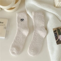 Dettaglio ravvicinato di calze accoglienti in pile corallo bianco con ricamo occhi - Taglia unica / Beige