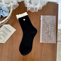Calcetines negros con bordes de volantes blancos y pequeños corazones sobre madera - Talla única / Negro