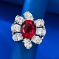 Macro shot of oval red ruby cluster ring with white gemstone halo in silver setting - US 5 / Red