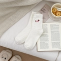 Detail von weißen flauschigen Korallenvlies-Socken mit süßer Dackel-Stickerei - Weiß