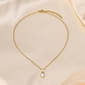Dettaglio della collana dorata con ciondolo rettangolare in madreperla e bordo perlato - Pendente con Catena