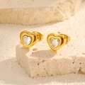 Macro detail of gold heart earrings with clear cubic zirconia on stone texture - Heart Studs