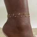 Detail of a triple-layer gold beaded anklet on an ankle over a minimal gray background - Gold Triple Layer Bead Chain (JC-135G)