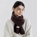 Sciarpa lavorata a maglia marrone scuro con etichetta tessuta su modella in studio - Caffè Scuro