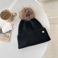 Chic black knitted winter hat with large faux fur pompom and metal logo accent - Ink Black