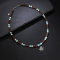 Bohemian surf necklace featuring dark wood beads, blue accents, and a silver sun pendant - Blue
