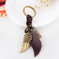 Llavero vintage de bronce con plumas de cuero marrón sobre un fondo de estilo rústico - Dorado