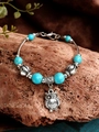 Detailansicht von Türkisperlen-Armband mit Eulenanhänger auf Holz und Stoffuntergrund - Eule Vintage Silber Türkis Stil