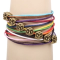 Pulsera trenzada multicolor con siete dijes de búho de bronce vintage en brazo de maniquí - Bronce