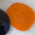 Transparenter orangefarbener Acryl-Untersetzer mit lachendem Gesicht auf Steintisch - Orange