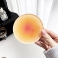 Round acrylic coaster with sunset gradient colors held by hand for nordic home decoration - Orange