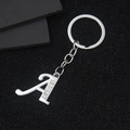 Silver letter A keychain with rhinestones and flat ring over a black textured background - Letter A