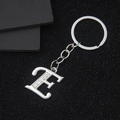 Silver metal letter E keychain with sparkling rhinestone accents on a black background - Letter E