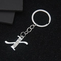 Silver letter K keychain with five inlaid rhinestones on a textured black surface - Letter X
