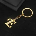 Golden alloy letter E keychain with sparkling rhinestone accents on a black background - Letter E Style / Gold