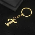 Golden letter T keychain with sparkling rhinestones on a textured black surface - Letter T Style / Gold
