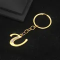 Golden cursive letter Z keychain with rhinestone accents on black textured fabric - Letter U Style / Gold