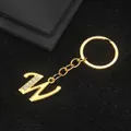 Golden metal letter W keychain with small sparkling rhinestones on a black background - Letter W Style / Gold
