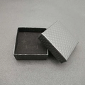 Close-up of square black jewelry gift box with textured finish and velvet lining inside - Black