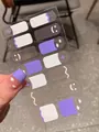 Makro-Detail von französischen Nagelstickern mit Smiley und Herz in Lila und Weiß - Einzelblätter