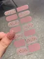 Makro-Detail von Glitzer-Fingernagelaufklebern in Pink und Gold, auf dem Daumen aufgeklebt - Rosa Gold Glitzer Stil