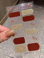 Nahaufnahme goldener Glitzer-Nagelsticker am Daumen mit roten und sternenklaren Designs - Blankes Blatt (PDD224)