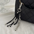Close-up of black tassel bag charm with metallic elements and silver spring clasp - Silver Beaded Style (00276)