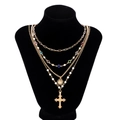 Macro detail of multilayer gold necklace with colorful crystals, pearls, and cross pendant - Gold